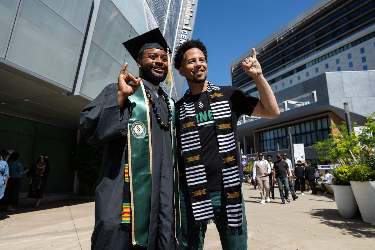 Sacramento State graduate Paul Lawrence Dunbar Banks makes the “stingers up” hand gesture with university President Luke Wood for a photo after the commencement ceremony at Golden 1 Center on Friday, May 17, 2024.