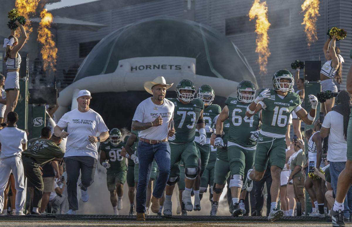 Sacramento State Hornets head coach Brennan Marion, center, runs onto the field before an NCAA football game against the Mercyhurst Lakers at Hornet Stadium on Saturday.