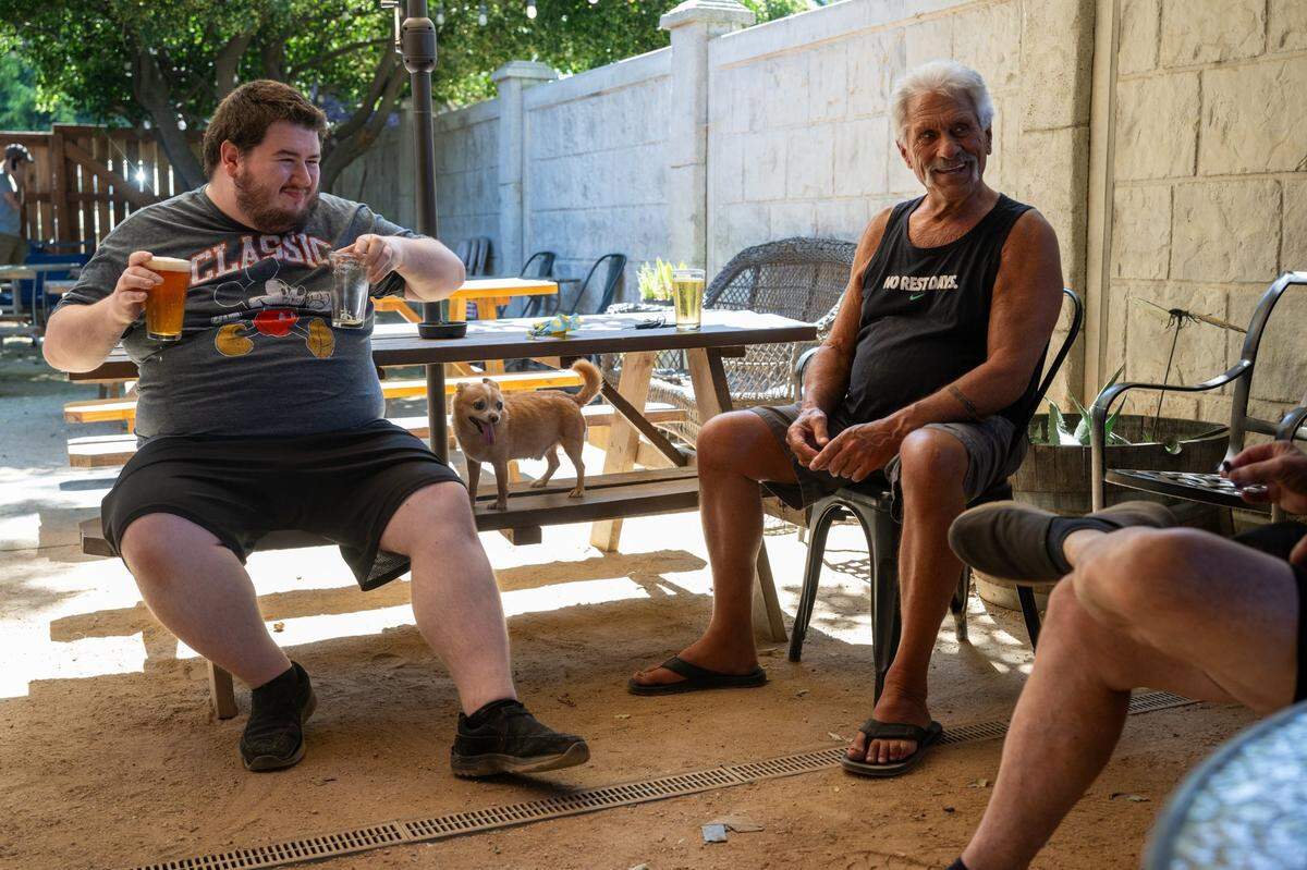 Kyle Mainer, left, and Gary McGrew with his dog Lucky relax in the patio area at The Trap on Monday.