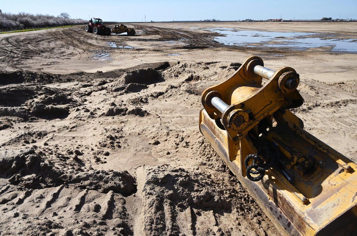 Heavy machinery in the distance grades and compacts a 20-acre basin on land operated by Markarian Family LP, as part of a project hoping to recharge the local aquifer. The recharging basin is adjacent to another 20 acres for a future basin. Photographed Friday, March 3, 2023 near Madera.