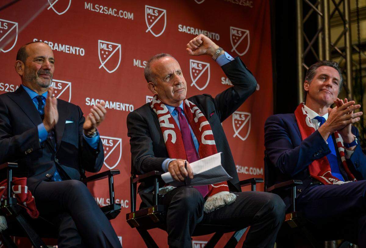 Sacramento Mayor Darrell Steinberg, middle, pumps his fist in the air during a press conference announcing Sacramento will get the 29th MLS franchise at The Bank in downtown Sacramento on Monday, Oct. 21, 2019. He sits between MLS Commissioner Don Garber, left, and California Gov. Gavin Newsom. The announcement turned out to be premature.