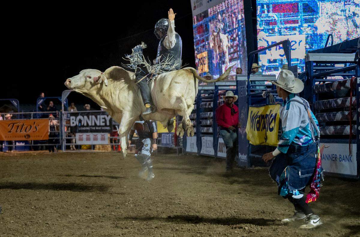 A bull rider attempts to hang on for the required 8 seconds during the Folsom Pro Rodeo on Thursday.