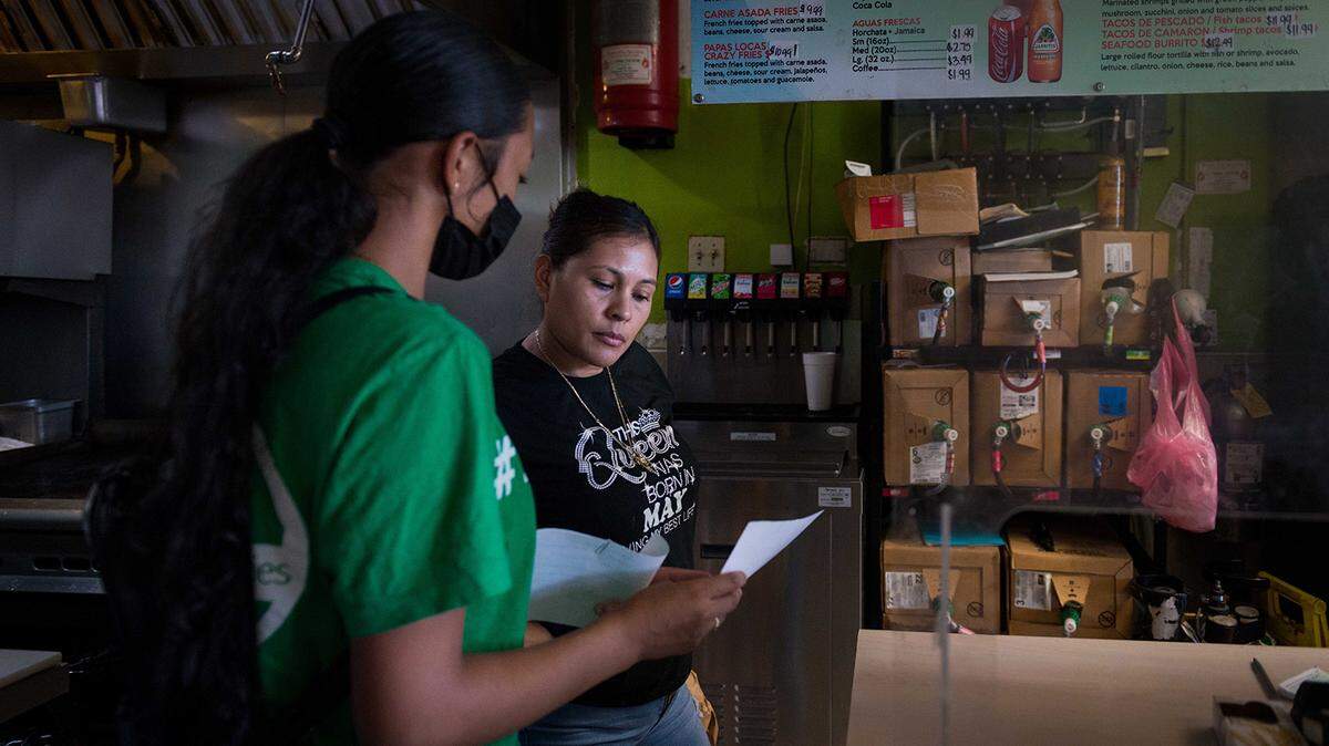 Melissa Lopez explains the COVID-19 testing process to a taco shop employee in Fresno as part of her training as a health educator.