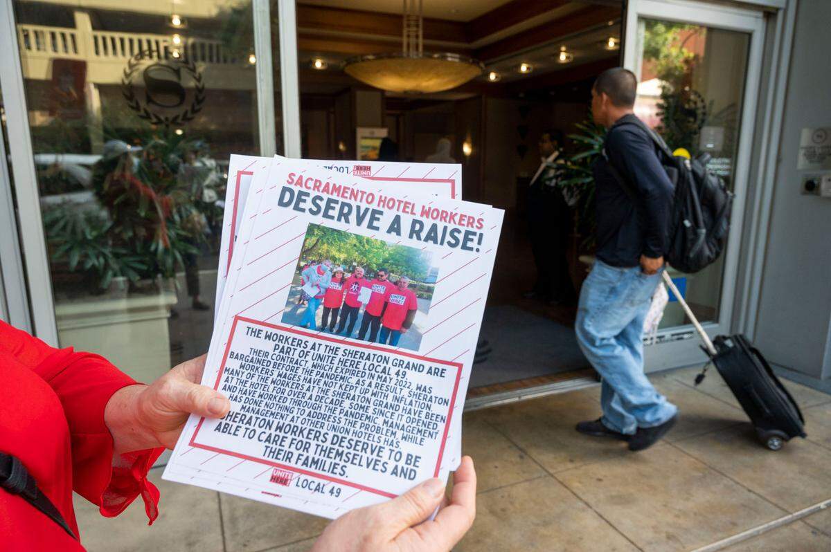 A hospitality worker from Local 49 hands out fliers in front of the Sheraton Grand Hotel in Sacramento on Wednesday during a rally to demand wage increases and address chronic short staffing.