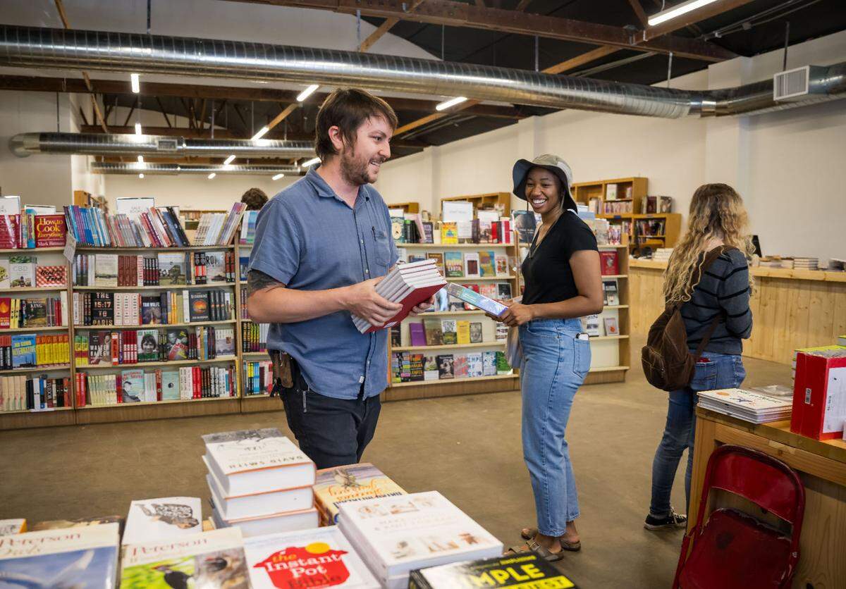 Beers Books manager Andrew Naify, left, organizes books while interacting with English Price, of Sacramento, during the longtime local bookstore’s soft opening at their new location at 712 R St. on Saturday, Aug. 26, 2023, in Sacramento. Price, 21 years old, said she had been visiting the bookstore at its previous location on S Street since she was 10 years old. “I want to help … keep the independents alive,” she said, adding she plans to return to the bookstore regularly.