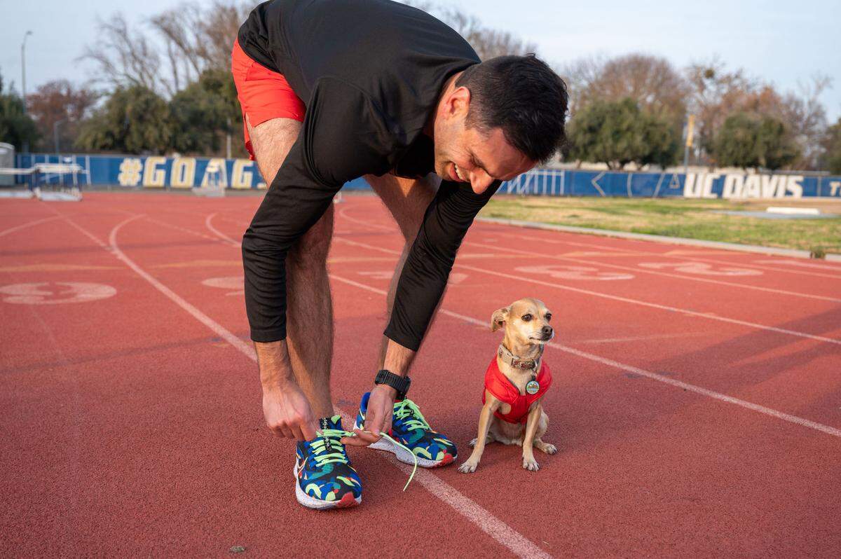 Andrew Owens ties his shoes as he and Jellybean get ready to run earlier this month at the track at UC Davis.. Jellybean has run marathons with him.