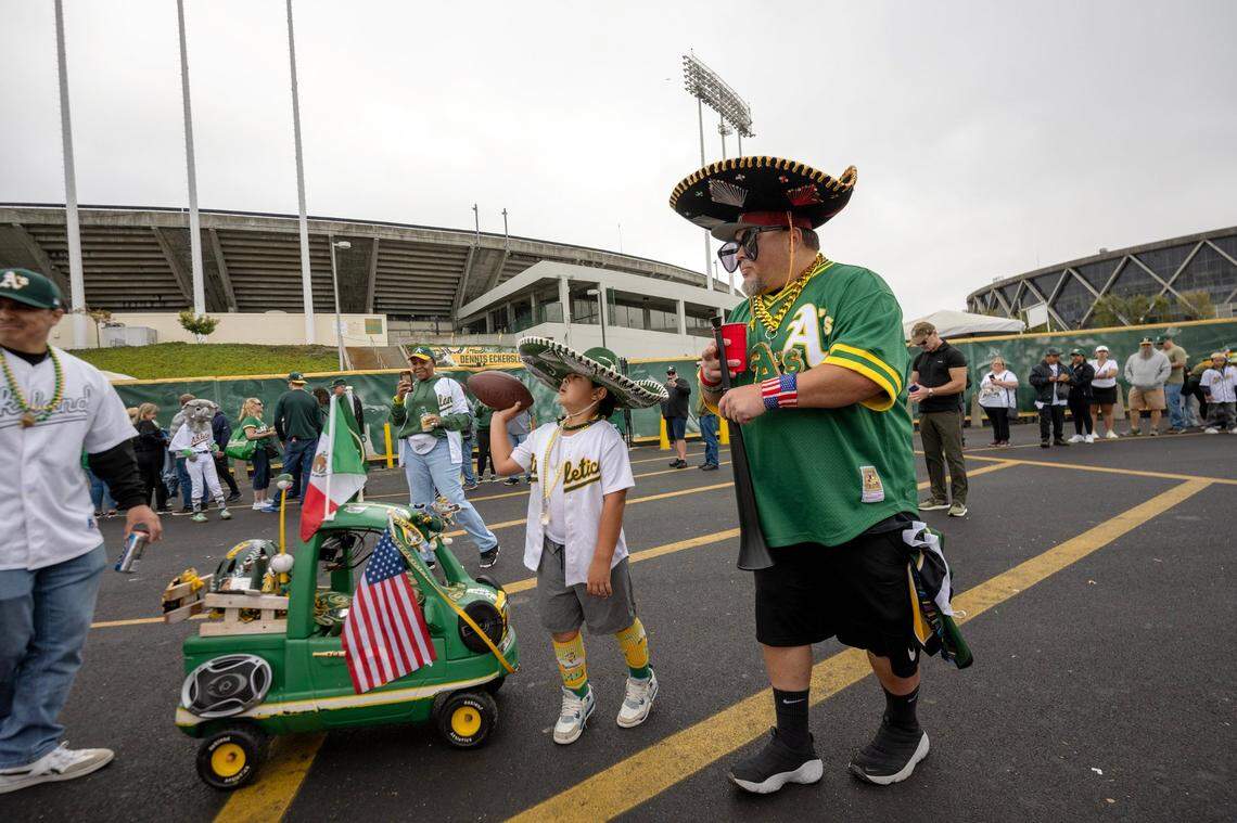 Cruz Munoz, 8, and his grandfather Sal Munoz of San Jose walk with their Athletics memorabilia attached to a kids cart outside of the Oakland-Alameda Coliseum before the A’s played their final game in Oakland on Thursday.