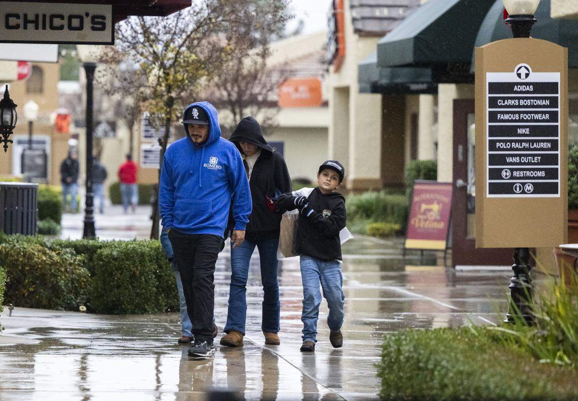 Gilbert Romero, of Valley Springs, shops with his wife Kayla and children Leo and Natalia as rain falls at the Folsom Premium Outlets on Monday, Dec. 22, 2025.