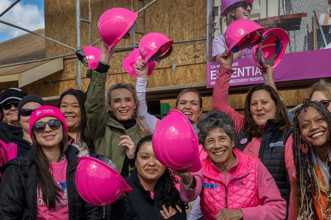 First Partner Jennifer Siebel Newsom, wearing green jacket, lifts her hard hat with other women leaders and legislator volunteers at a Habitat for Humanity event celebrating International Women’s Day in Sacramento on Wednesday.