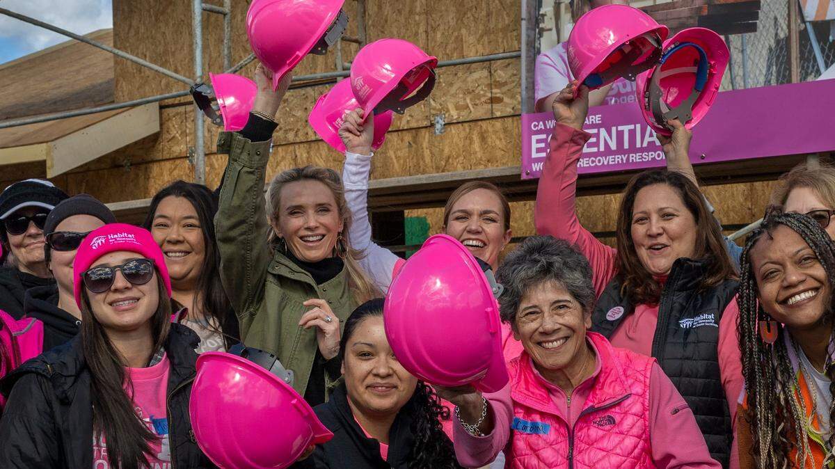 First Partner Jennifer Siebel Newsom, wearing green jacket, lifts her hard hat with other women leaders and legislator volunteers at a Habitat for Humanity event celebrating International Women’s Day in Sacramento on Wednesday, March 8, 2023.