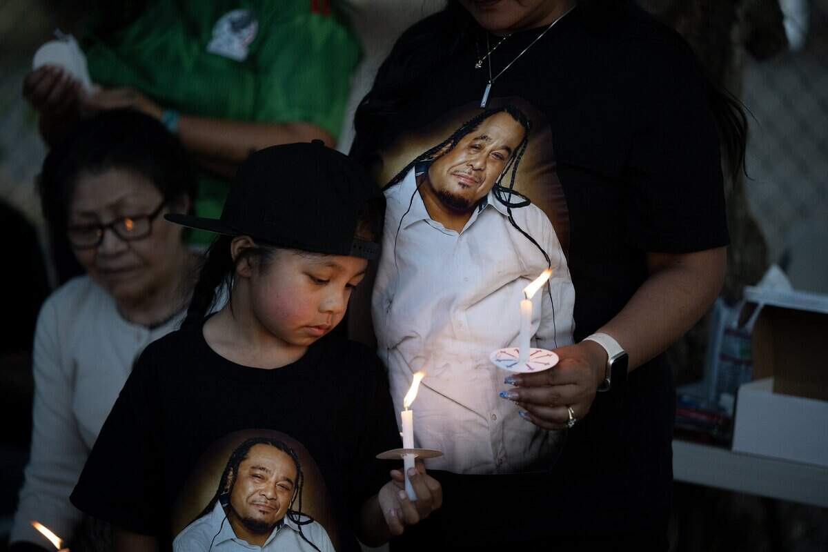 Quincey Bocos is surrounded Wednesday by images of his father Christopher Bocos as he holds a candle during a vigil to honor his father and six others who died in the Esparto fireworks explosion, on the first anniversary of the tragedy.