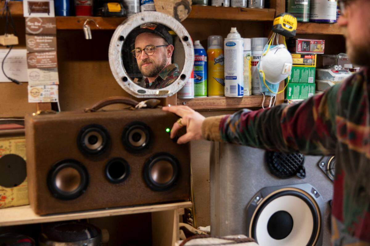 Kaden Hill of Rare Bird Steros adjusts the volume on a bluetooth speaker cabinets he created out of an old 1940s suitcase in his garage workshop in Sacramento on Tuesday, Jan. 11.