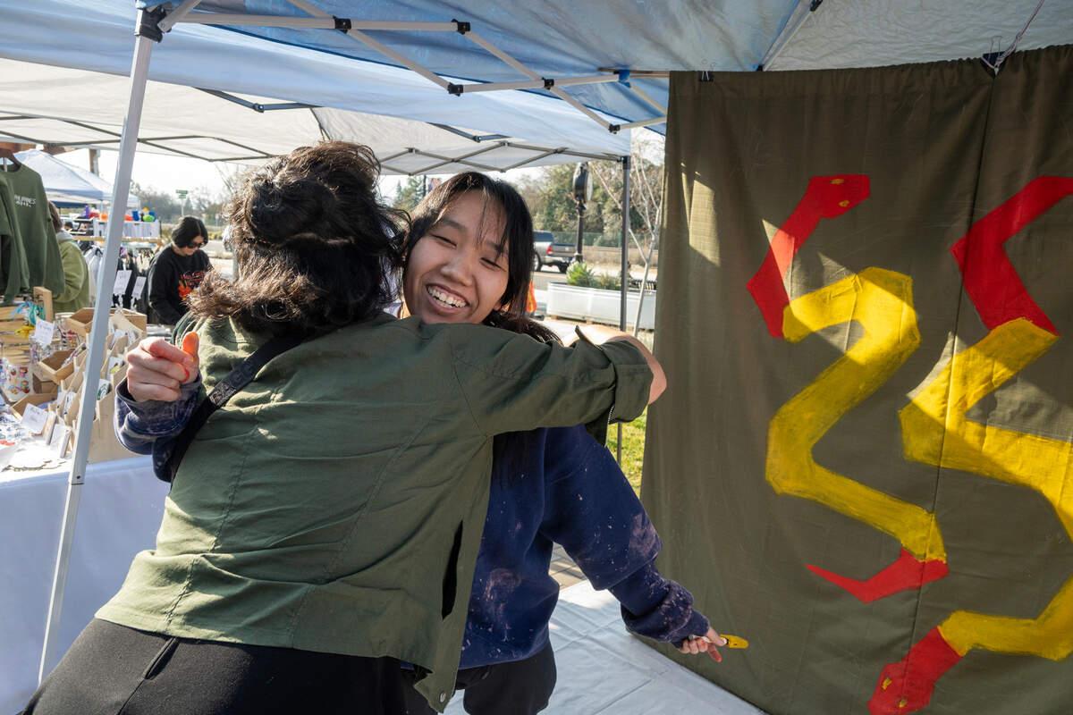 Artist Karen Tsugawa takes a break from her painting to embrace her friend Evi Pineschi at the Elk Grove Lunar New Year in Old Town Plaza on Saturday.