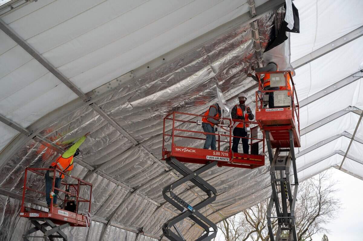 Workers install insulation on a Sprung shelter for the homeless Feb. 11, 2021, off of Broadway near Alhambra Boulevard on the edge of Oak Park and Curtis Park.