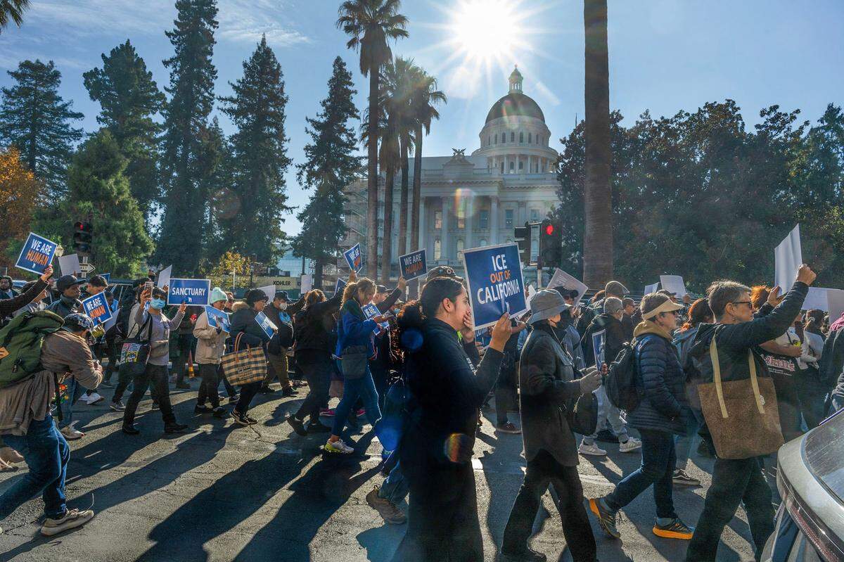“ICE of out California,” reads a sign as hundreds march on L Street around the state Capitol in Sacramento to oppose mass deportations and protect immigrant Californians on Monday.