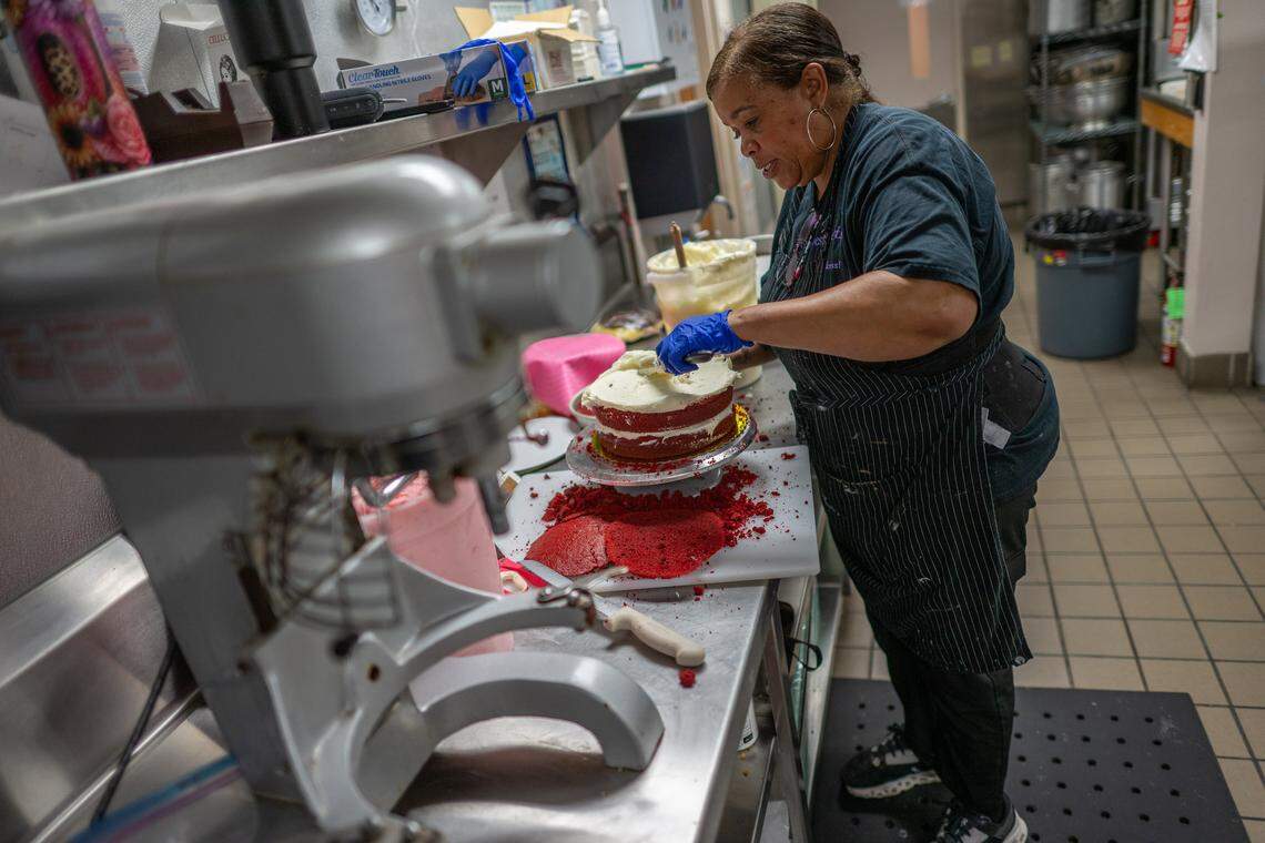 Terri Littleton, 63, a self-employed owner of Terri Does Desserts, spreads cream cheese icing on a red velvet cake in an industrial kitchen in Sacramento on Wednesday, April 1, 2026. The baker supplies desserts to several restaurants and coffee shops. Escalating costs for ingredients, gas, rent, and healthcare have made life very challenging, she said.