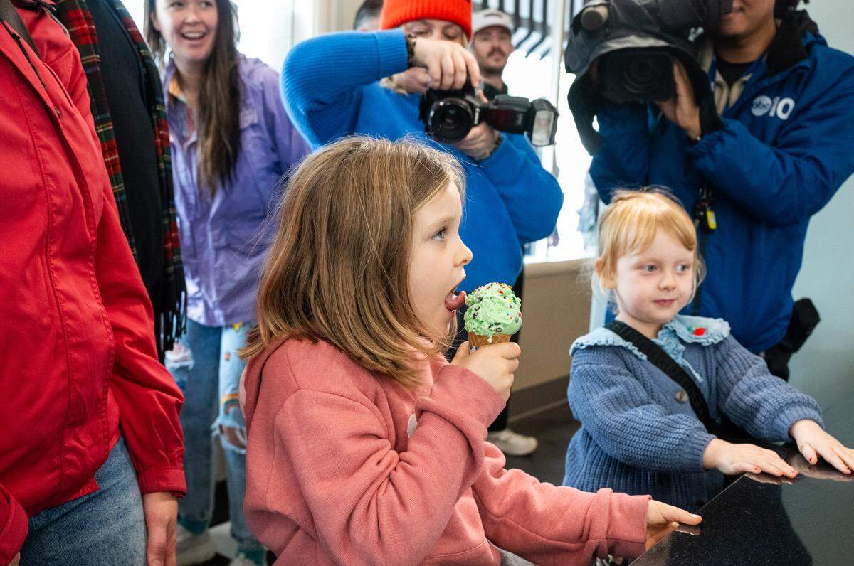 Under the watchful view of the assembled cameras, Margot Arieas licks the first ice cream cone served – mint chip with sprinkles – at the reopening of at Vic’s Ice Cream in Sacramento on Saturday.
