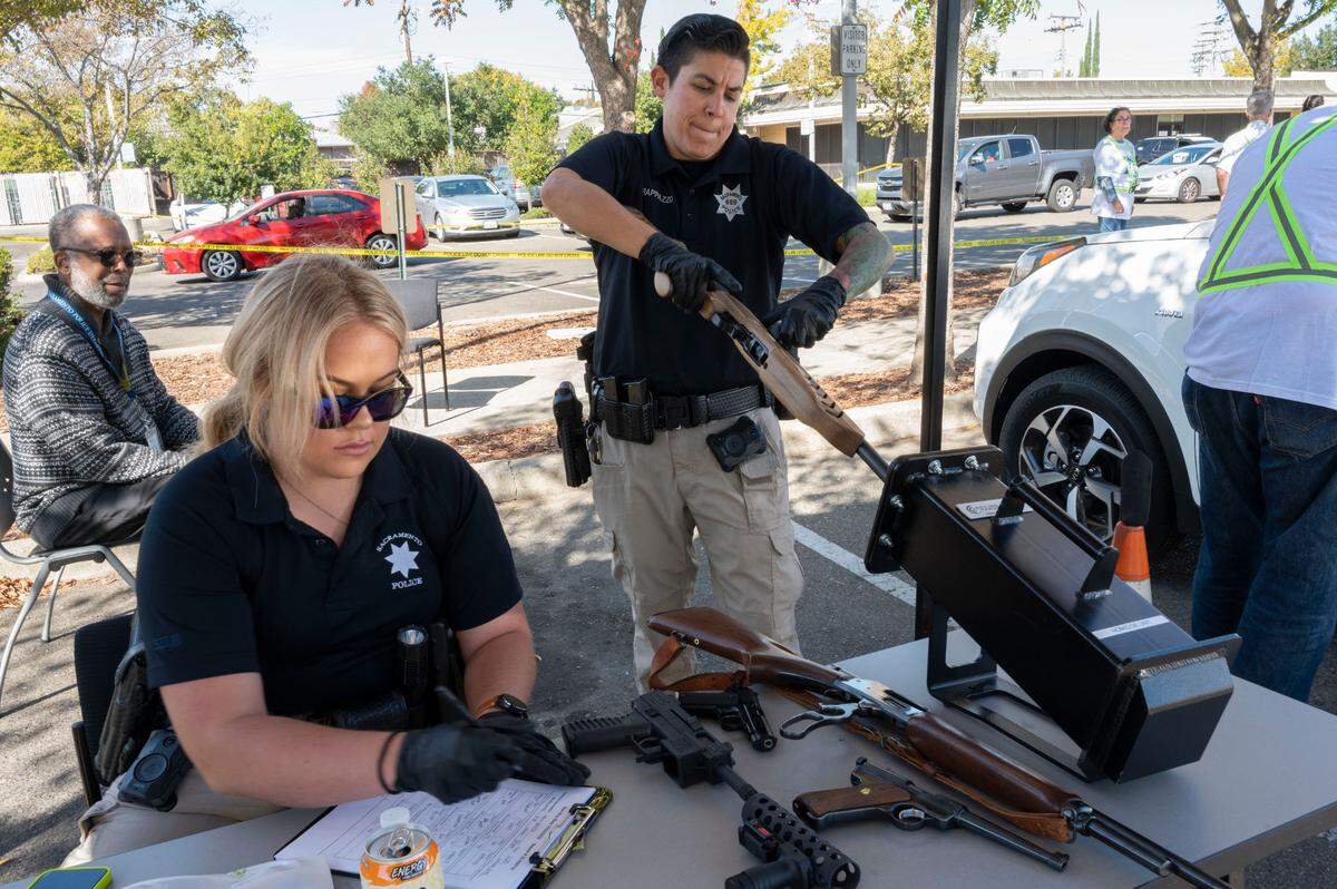 Officers Lindsey Smith, left, and Katie Rappazzo test firearms to make sure they function usintg a firing tube while logging a donation at the Sacramento Police Department’s gun buyback event on Saturday.