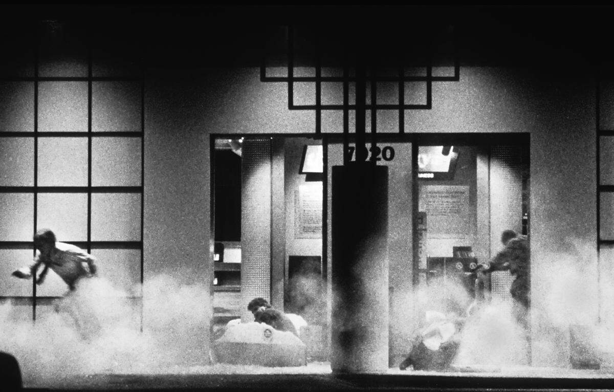 A gunman, right, begins to shoot hostages tied up on the ground at the Good Guys store on April 4, 1991, as smoke from a tear gas canister fills the area.