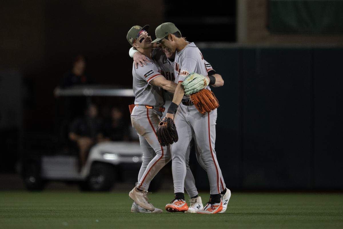 San Francisco Giants outfielders Drew Gilbert, left, Harrison Bader, center, and Jung Hoo Lee embrace following the 6-4 victory over the Athletics on Saturday at Sutter Health Park in West Sacramento.