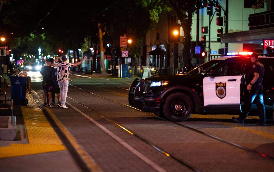 People leaving Dive Bar and District 30 in Downtown Sacramento walk past a police presence in the area as bars and nightclubs prepare to close after a Friday night in September on the 1000 block of K Street.