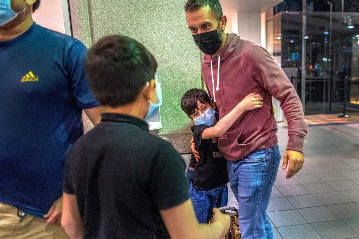 Ethel I. Baker Elementary School Principal Nate McGill is hugged by student Raihan, 6, and approached by his brother Faizan, 8, upon their arrival to Sacramento International Airport on Thursday. The school children had been trapped in Afghanistan along with their sister Pakiza, 9, and parents after the country fell to the Taliban. McGill was the families lifeline to safety back to Sacramento.
