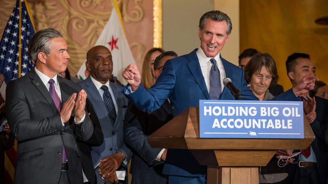 Gov. Gavin Newsom is surrounded by legislators and state officials — including state Attorney General Rob Bonta, left, and state Sen. Nancy Skinner, D-Berkeley, right — as he speaks before signing a bill at the Capitol on Tuesday, March 28, 2023, aimed at addressing gas price gouging.