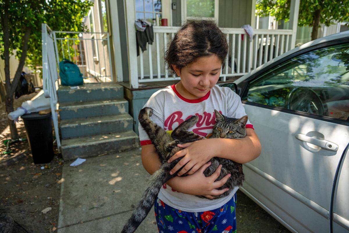 Leilani Reyes, 9, cradles her cat, Chicola, on Tuesday outside a city-funded cottage in Sacramento where she has been living since February with her mother, Tana Saito, and four siblings. The city has changed the program, and the family is unsure where they will go.