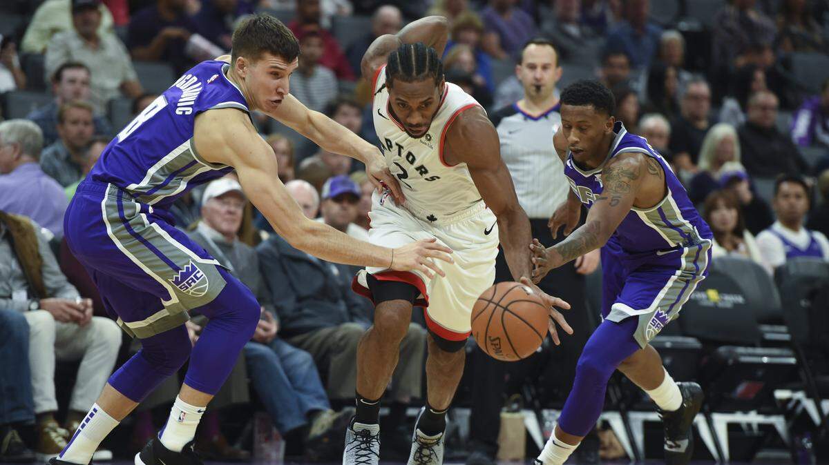 Kings forward Troy Williams, right, and guard Bogdan Bogdanovic try to defend Toronto Raptors forward Kawhi Leonard on Wednesday at Golden 1 Center.