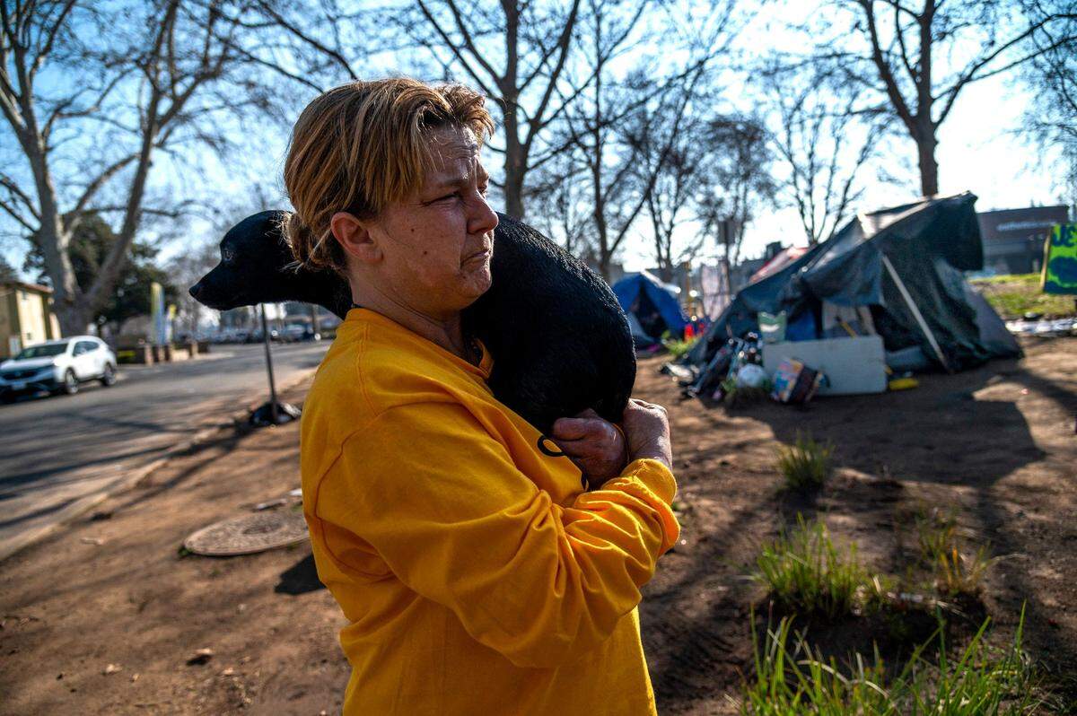 Joy Gonzalez, 50, holds her dog Durango, as she explains Friday why she moved from the river to a homeless encampment on Fair oaks Boulevard and Howe Avenue. “I’ve been beaten up and held against my will. I’ve had my dog stolen from me—my best friend,” said Gonzalez who said she feels safe now.
