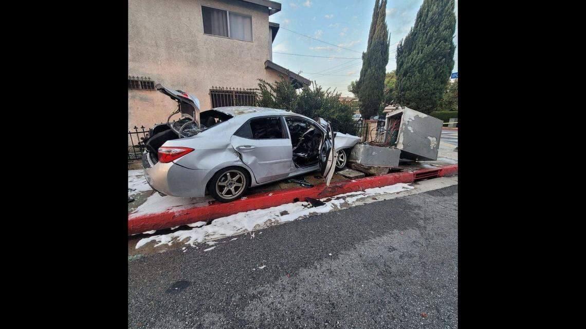 Police rescued an unconscious woman who was trapped in a burning car after it hit a traffic signal control cabinet on a California sidewalk, officials said.