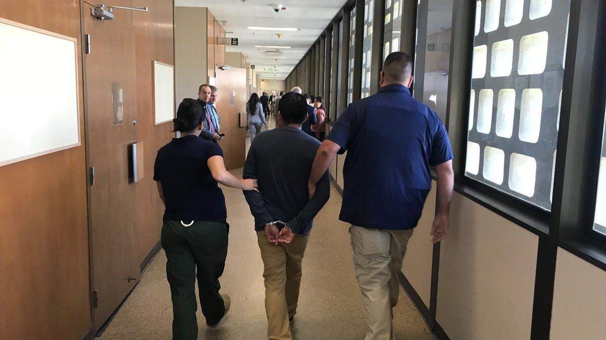 ICE agents lead a suspect down the hall of Fresno County Superior Court in July. Agents have been making arrests inside the Fresno County courthouse for weeks.