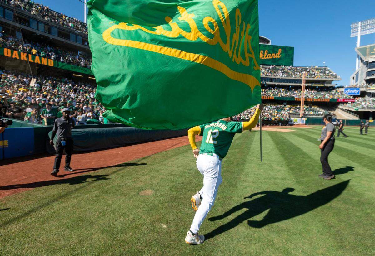 The Oakland A’s Mark Schuemann runs with a team flag after the final home game at Oakland-Alameda County Coliseum on Thursday.