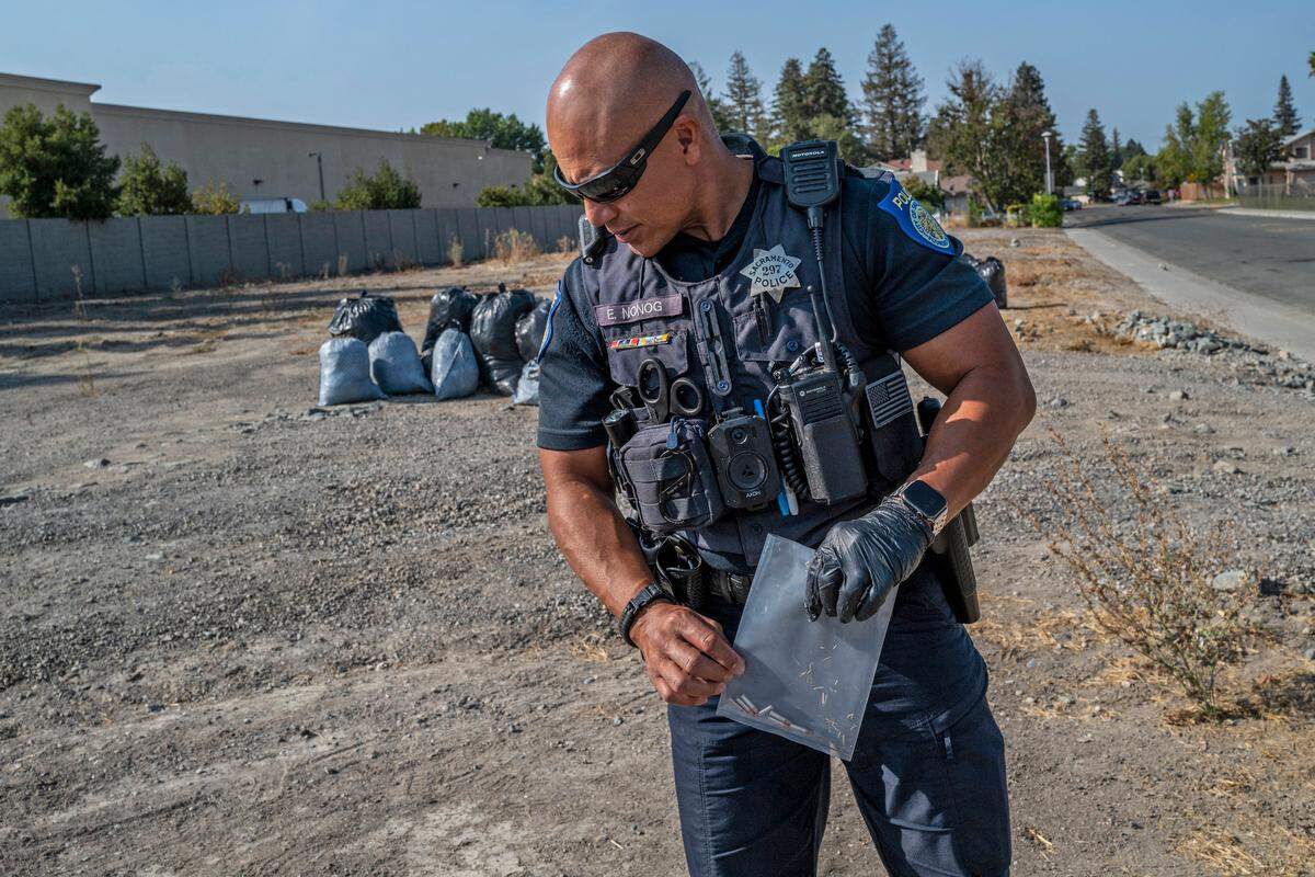 Sacramento Police officer Ed Nonog picks up bullets across the street from Garden Valley Elementary School in South Natomas on Friday. A member of the City of Sacramento Department of Community Response called the police while they were answering a 311 call from parents concerned because there is a small homeless encampment across from the school. Seven unspent bullets were found.