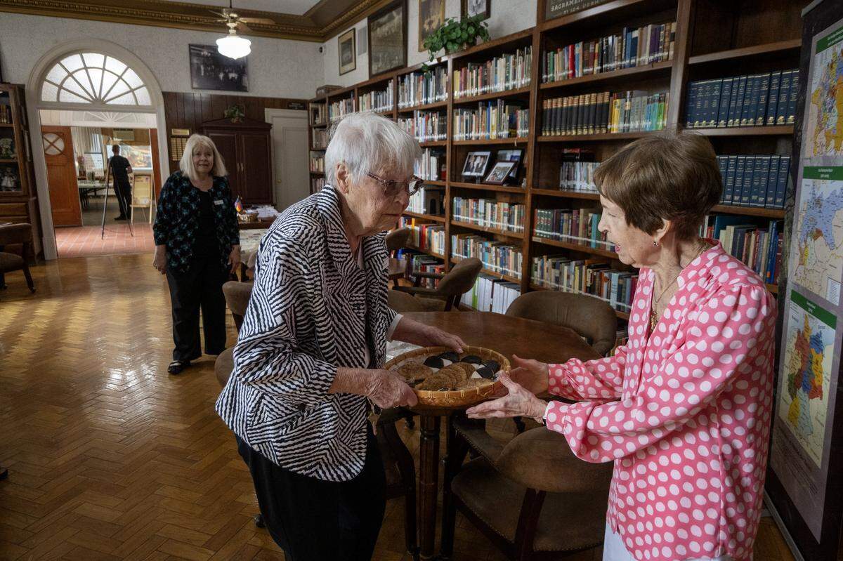 Iise Laudi, a member of Sacramento Turn Verein, passes cookies to Susie Pelz, president of the library at Turner Hall, on April 25 as the club celebrates the 100-year anniversary of its building.