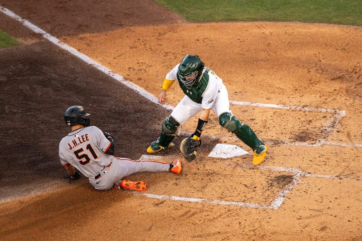 Athletics catcher Shea Langeliers (23) attempts to apply a tag as San Francisco Giants outfielder Jung Hoo Lee slides into home plate during a baseball game at Sutter Health Park in West Sacramento on Saturday, July 5, 2025.