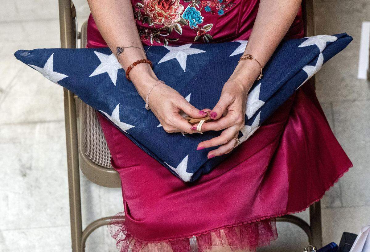 Michelle Silva holds a puzzle piece and an American flag given to her by a Marine honor guard during the funeral for her husband José Luis Silva at East Lawn Cemetery in Sacramento.