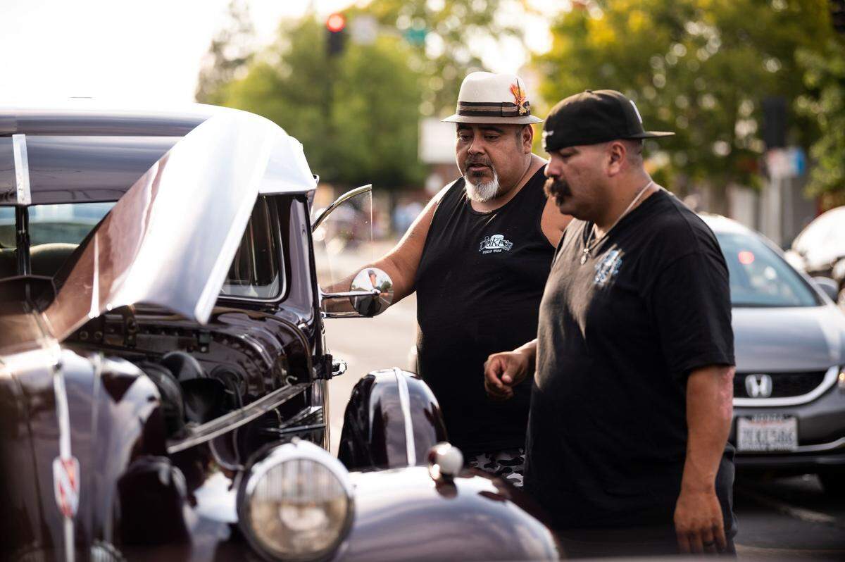 Joe Carmona, left, helps Carlos Rodriguez – both members of Dukes Car Club – as they look under the hood of ShaVolla Rodriguez’s 1939 Buick Touring on July 31, 2021.