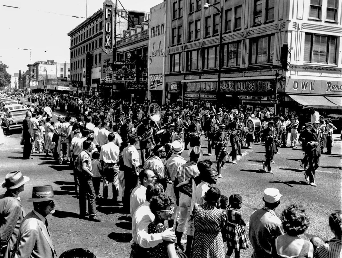 Crowds line the sidewalks as the C.K. McClatchy High School band marches down K Street in the Memorial Day parade on Thursday, May 30, 1957. The Fox Senator Theatre, at 912 K Street, and the Hotel Regis, at 1106 11th Street, are visible.