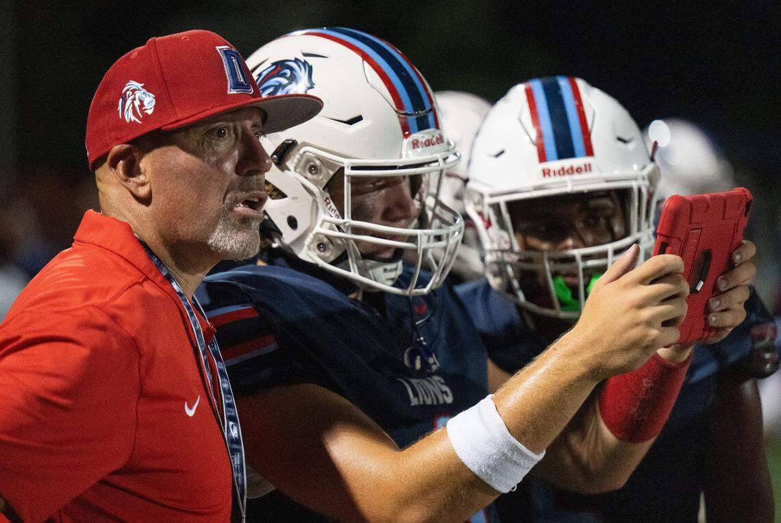 Destiny Christian Lions quarterback Dallas Munn, center, looks at a tablet with coach Aaron Garcia on Friday.