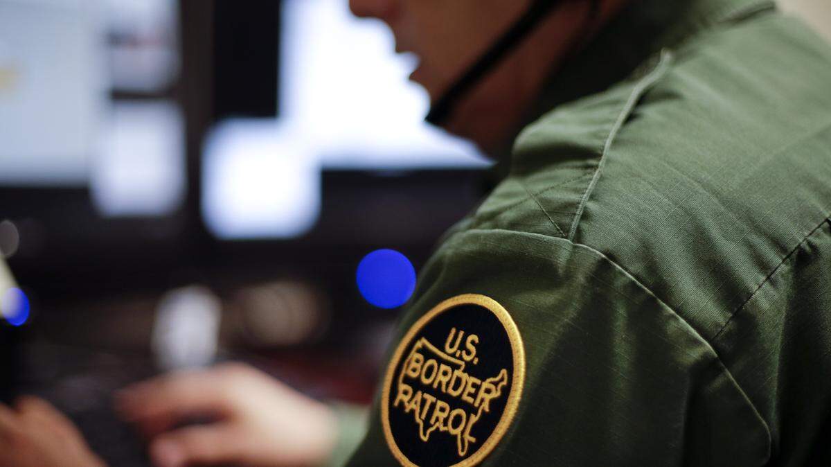 A Border Patrol agent uses a headset and computer to conduct a long distance interview by video from a facility in San Diego.