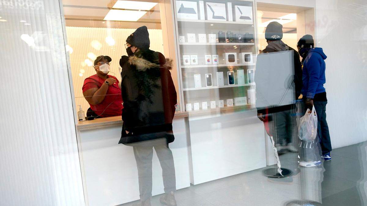 Customers pick up online orders at the Apple Store at the Towson Town Center, Tuesday, Dec. 15, 2020, in Towson, Md. The store has been remodeled to accommodate pick-up only with no in-store access to help stop the spread of COVID-19. (AP Photo/Julio Cortez)