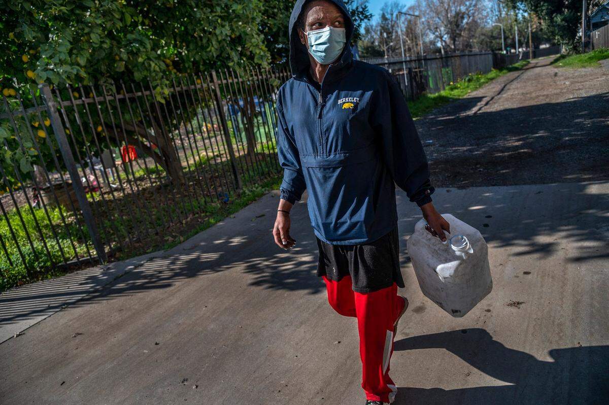 Timell Brown holds a jug as she looks for water near her camp. She found a faucet at an apartment complex.