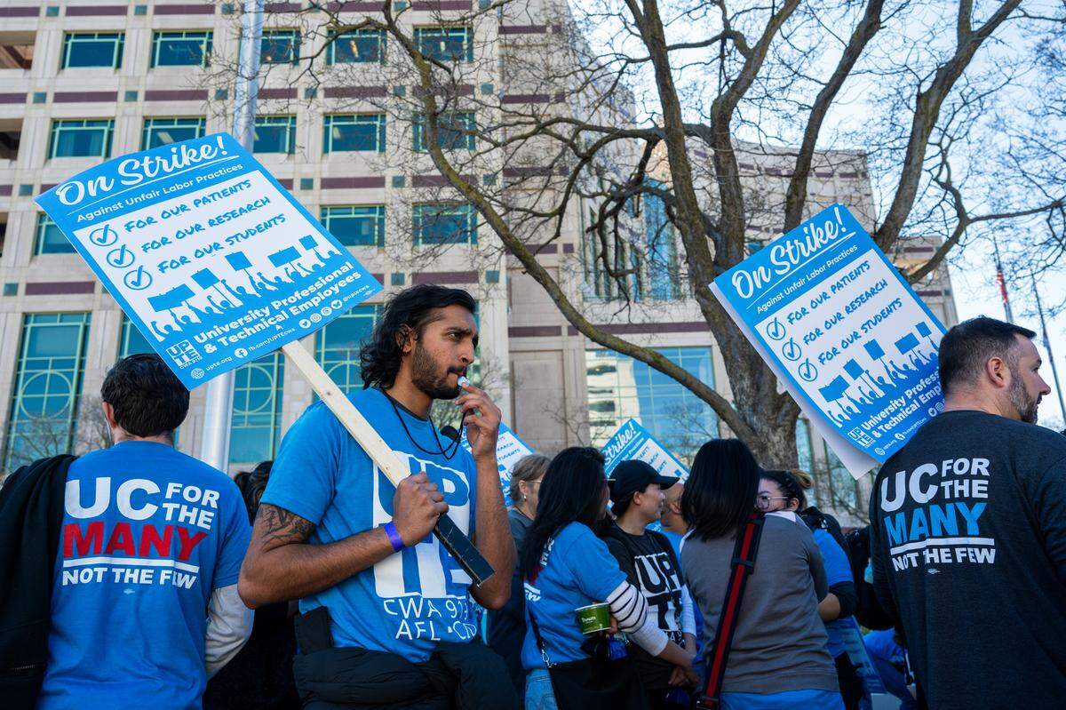 Sudev Namboodiri blows a whistle while walking the picket line at UC Davis Medical Center in Sacramento on Wednesday. According to organizers, 4,000 health care, research and technical workers at the facility will be on strike through Friday over unfair labor practices and a staffing crisis.