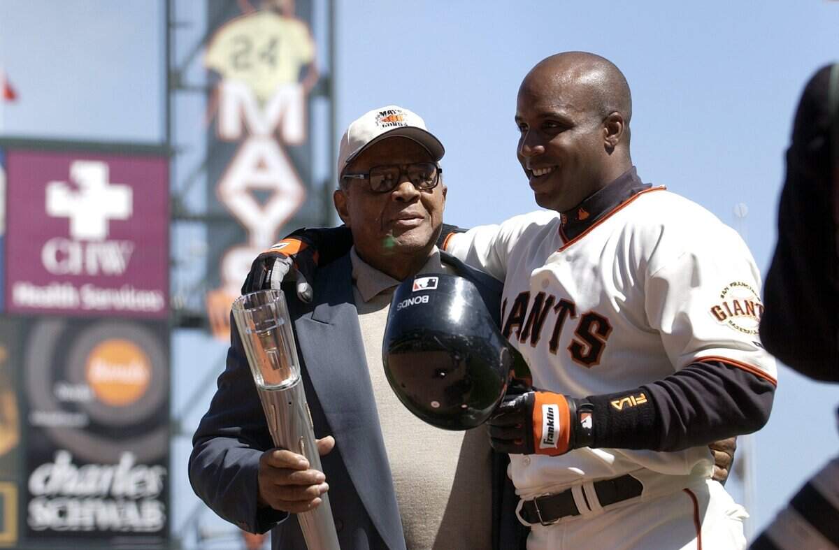 Barry Bonds, de los San Francisco Giants, recibe una antorcha de su padrino Willie Mays tras conseguir su 660º jonrón, empatando el récord de Mays, en el SBC Park de San Francisco, el 12 de abril de 2004.