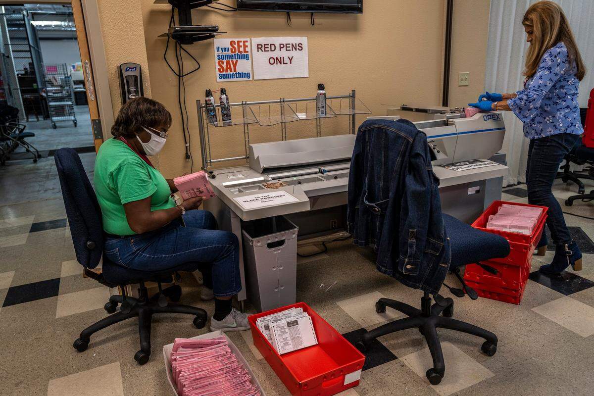 Temporary election clerks Jacqueline Henderson, left, and Narda Erickson, right, extract ballots from envelopes at the Voter Registration and Elections Office in Sacramento on Thursday. The public is invited to sign up for tours to view the process.