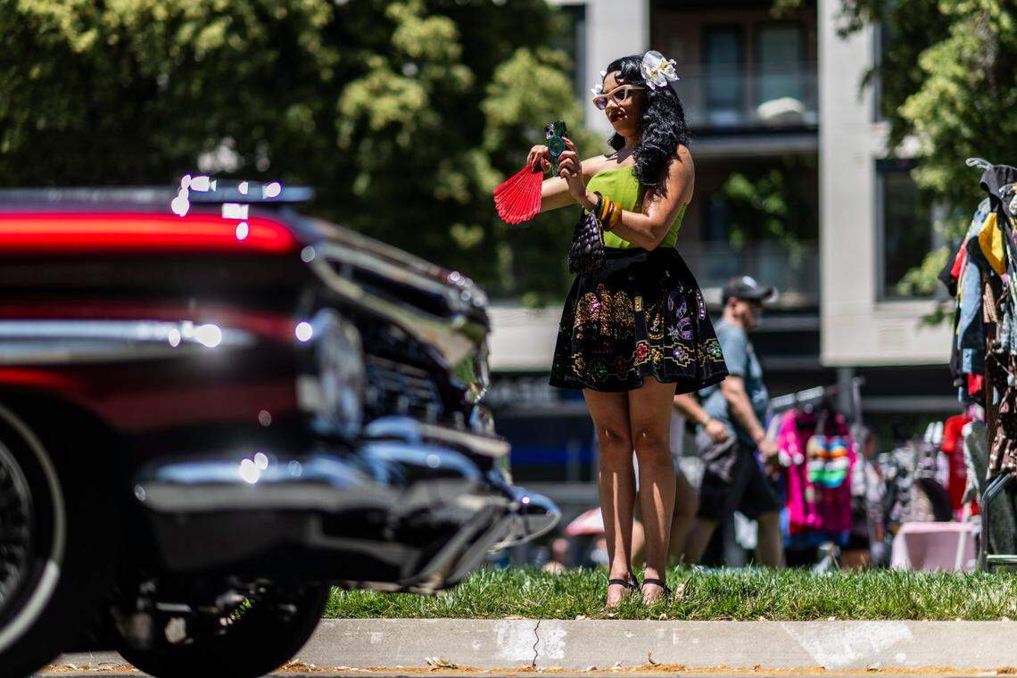 Maria Ballesteros, of Fresno, records lowriders as they cruise on Capitol Mall during the California Lowrider Holiday Celebration on Sunday.
