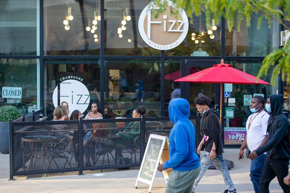 A group walks past Fizz Champagne & Bubbles Bar at Downtown Commons in Sacramento on Sunday.