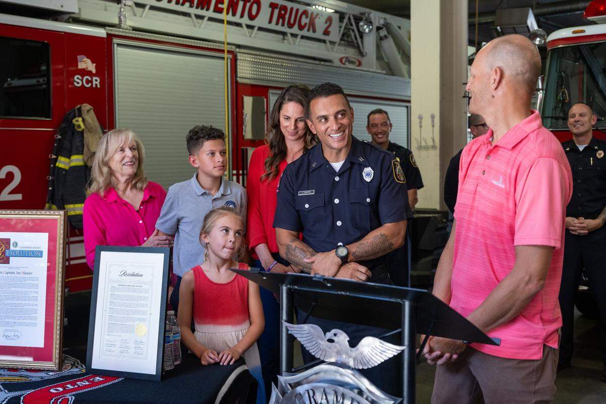 Mayor Kevin McCarty, right, introduces Sacramento Fire Capt. Joe Hunter during a ceremony at Fire Station No. 2 on Monday to honor Hunter for his advocacy on behalf of domestic violence victims and their families, his service to Sacramento as a firefighter, and the bravery he displayed on the reality TV show “Survivor.” He was joined by his family, from left, mother Patricia Hunter, children Joseph and Jayde, and wife Kayte Christensen.