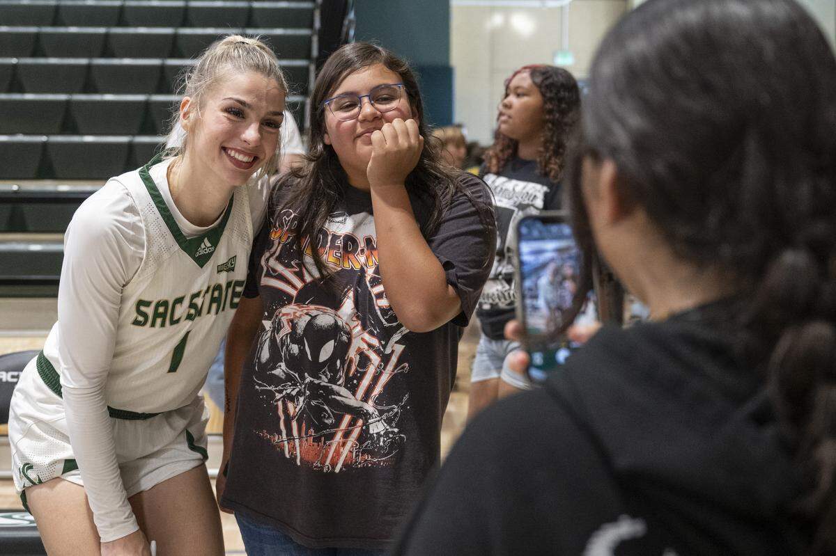Sacramento State guard Benthe Versteeg (1) takes photos with visiting school kids after a game against Nevada at Hornet Pavilion in Sacramento on Thursday, Nov. 6.